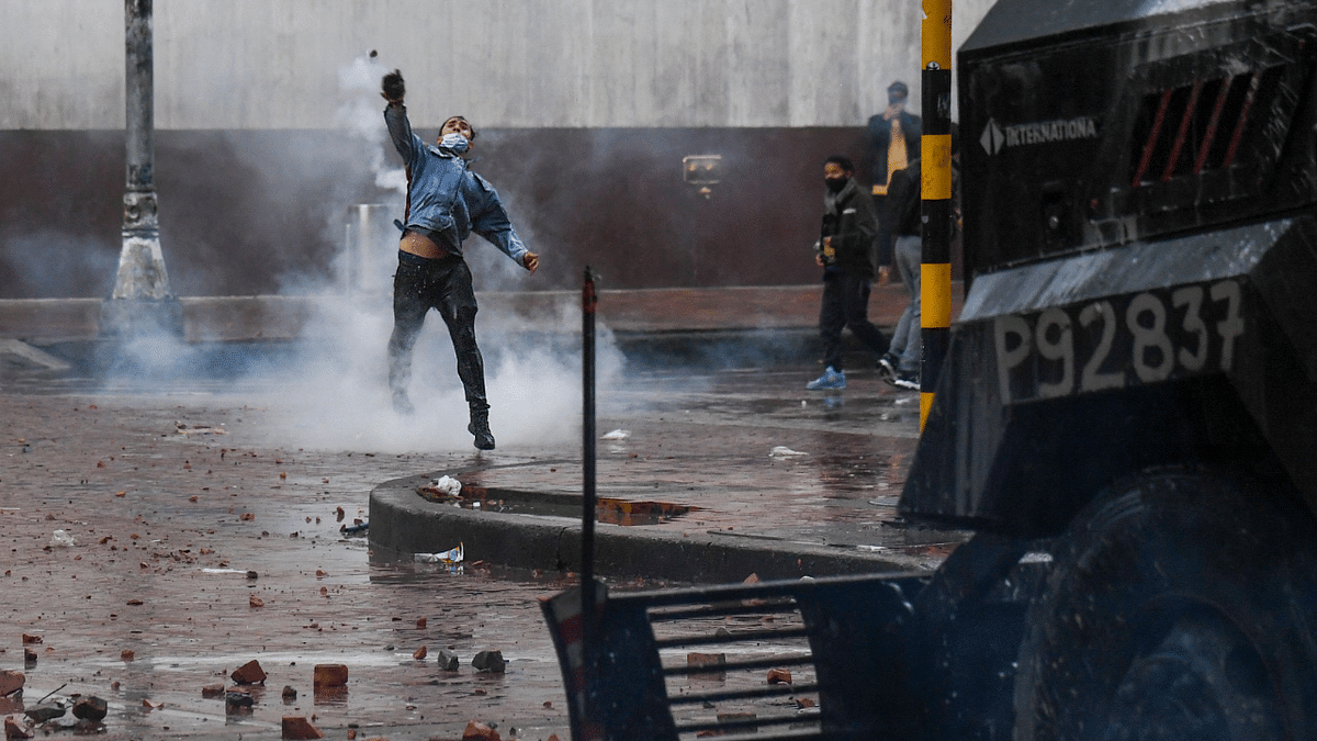 A demonstrator throws a stone at riot police vehicle during a protest against President Ivan Duque's government at the Bolivar square in Bogota. Credit: AFP Photo