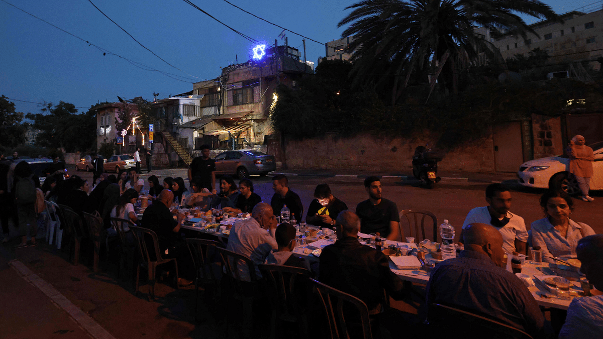 Palestinians gather for an Iftar meal, the evening meal with which Muslims end their daily Ramadan fast at sunset,in front of an Israeli settler's house as Palestinian families face eviction, part of an ongoing effort by Jewish Israelis to take control of homes in the Sheikh Jarrah neighbourhood of occupied east Jerusalem. Credit: AFP Photo