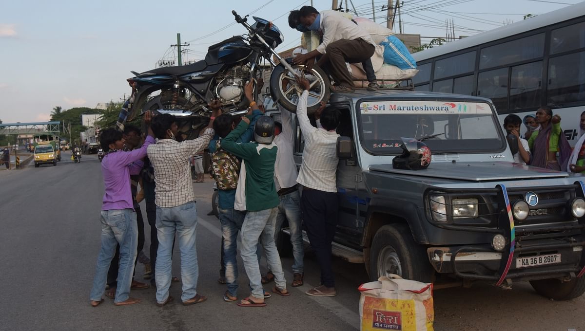 Migrant people load a motorbike on a pickup van as they leave the city before the statewide lockdown imposed to combat coronavirus, in Bengaluru.
