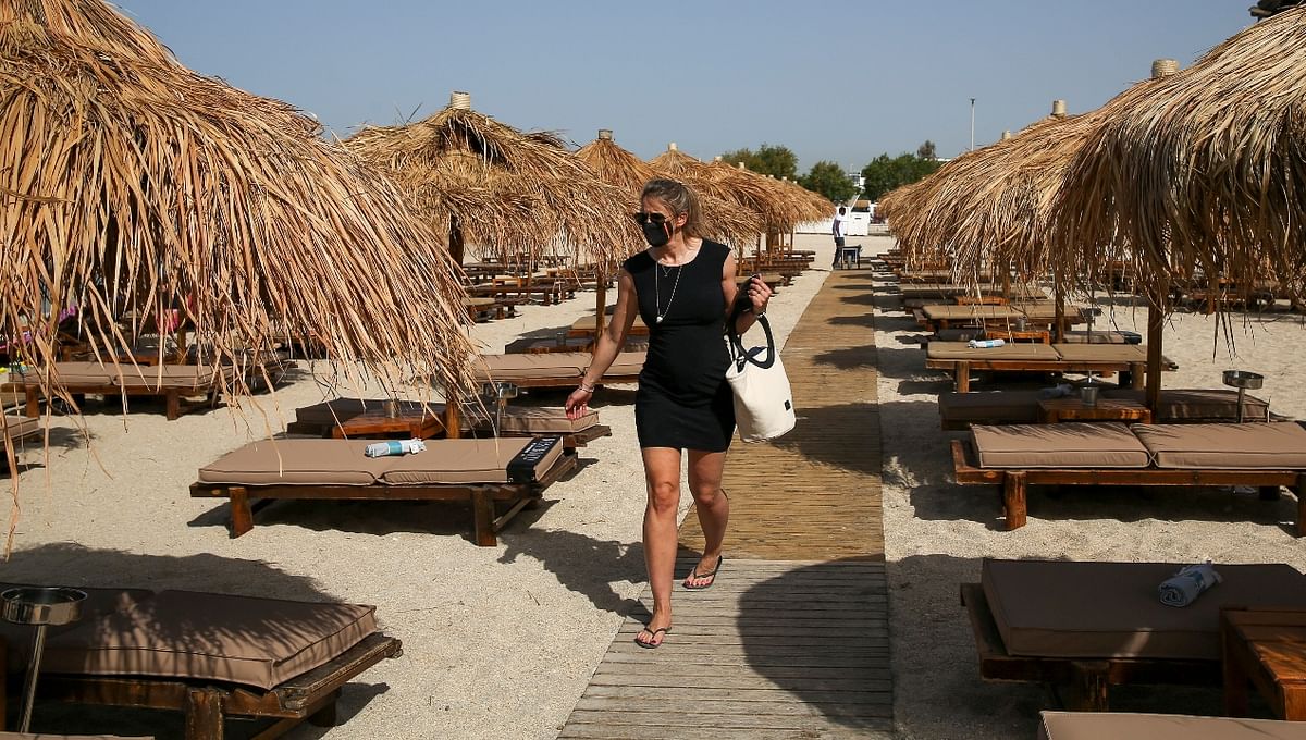 A woman wearing a protective face mask walks among empty sunbeds during the official reopening of beaches to the public, following the easing of measures against the spread of the coronavirus disease (Covid-19), in Athens, Greece.