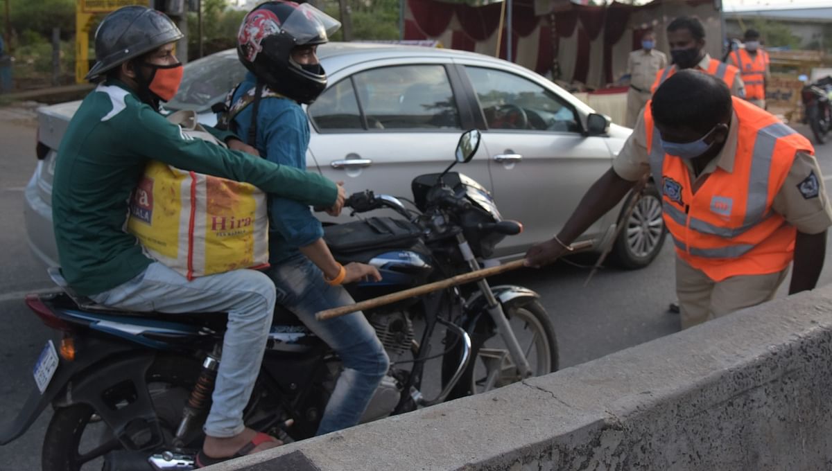 A policeman wields his baton at a bike rider in Bengaluru.