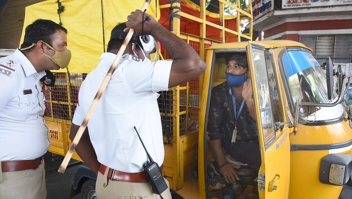 A policeman wields his baton at an autorickshaw driver for breaking the lockdown rules.