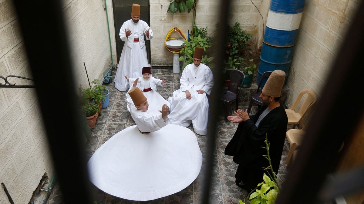 Sufi Dervish dancer Mahmoud al-Kharrat (R), 34, applauds other members of his family as they dance at a courtyard in their house in the Shahgur district of the old city of Syria's capital Damascus. Credit: AFP Photo