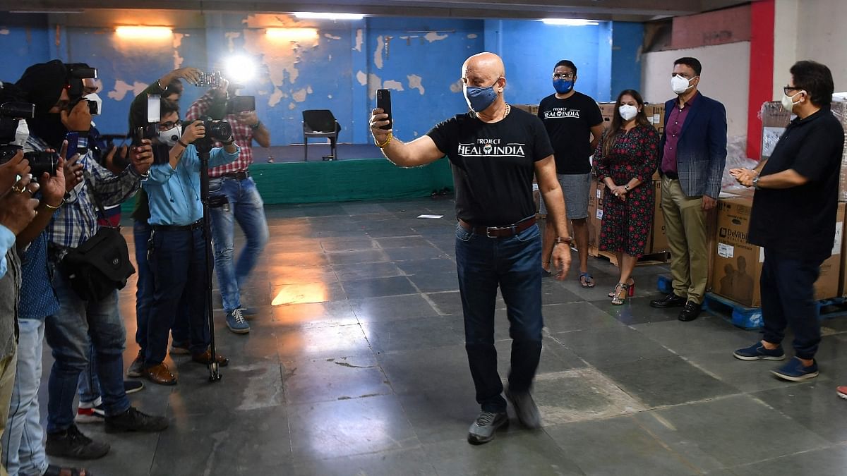 Actor Anupam Kher is seen taking pictures of the gathered media persons.