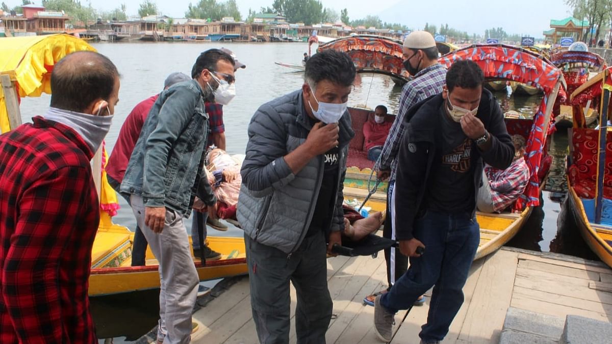 People wearing face masks steps out of a Shikara at a deserted Dal Lake in Srinagar.