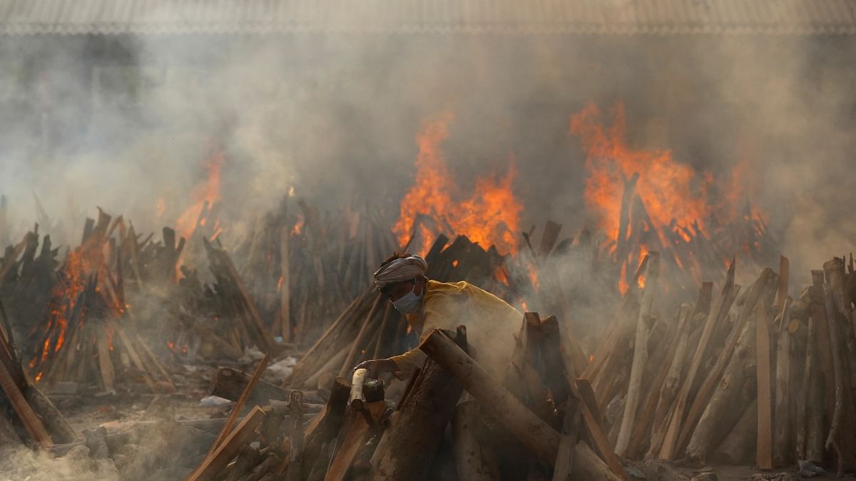 A man prepares a funeral pyre during a mass cremation covid-19 victims at a crematorium in New Delhi. Credit: Reuters Photo