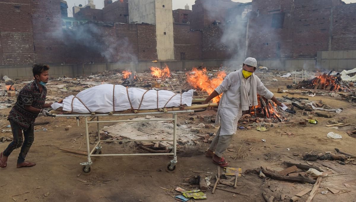 A Muslim man helps his friend in cremating his family member in New Delhi. Credit: PTI Photo