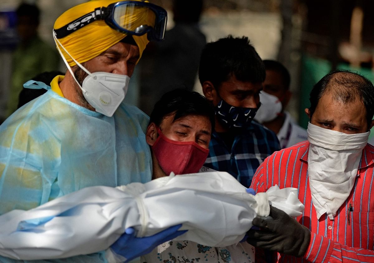 A man mourns as he with volunteers prepare to perform the last rites of a child who died of Covid-19 coronavirus at a crematorium in New Delhi. Credit: AFP