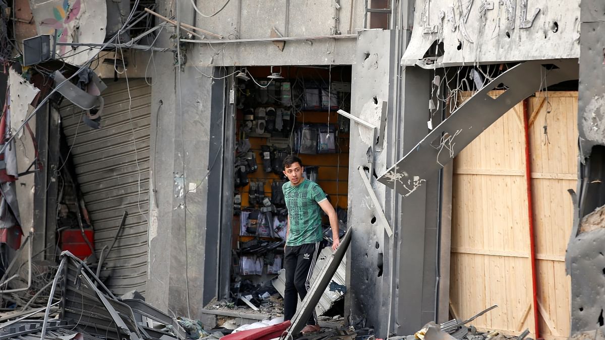 A Palestinian man stands outside a damaged shop. Credit: Reuters Photo