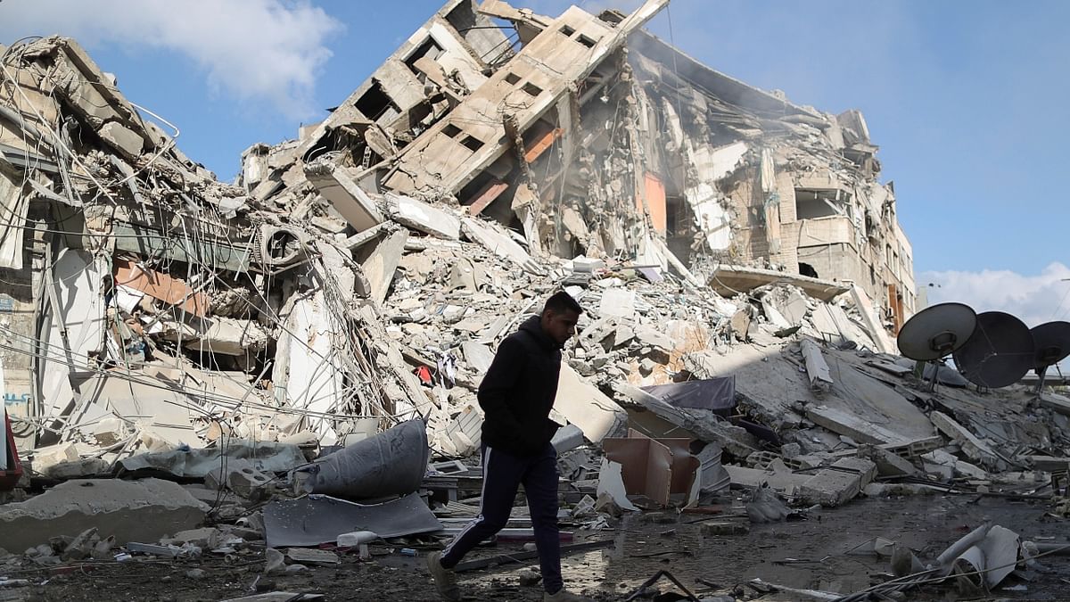 A Palestinian man walks past the remains of a tower building which was destroyed by Israeli air strikes. Credit: Reuters Photo