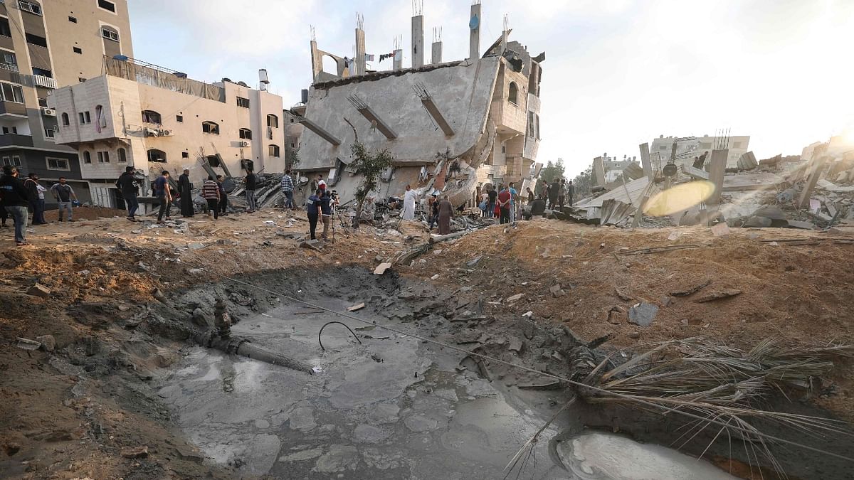 People and journalists gathered in front of a destroyed building in the northern Gaza Strip town of Beit Lahia on May 13, 2021. Credit: AFP Photo