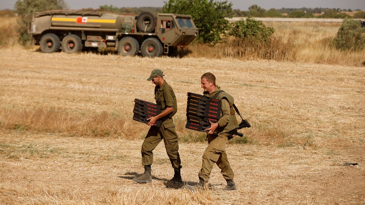 Israeli soldiers carry boxes of pizza in a field in Israel near the border between Israel and the Gaza Strip.