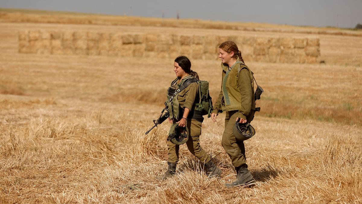 Israeli soldiers walk in a field in Israel near the border between Israel and the Gaza Strip.