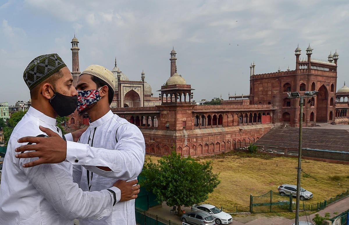 Muslim devotees greet each other on the occassion of Eid al-Fitr, marking the end of the fasting month of Ramadan, during the ongoing COVID-induced lockdown, near Jama Masjid in New Delhi. Credit: PTI Photo