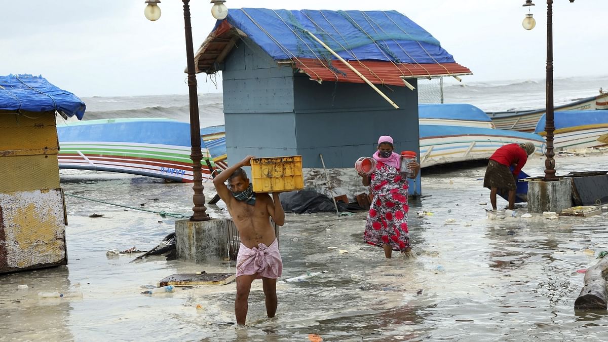 People carry belongings as they move away from the sea shore, after a red alert due to the formation of Cyclone Tauktae, at Baypore in Kozhikode, Kerala.