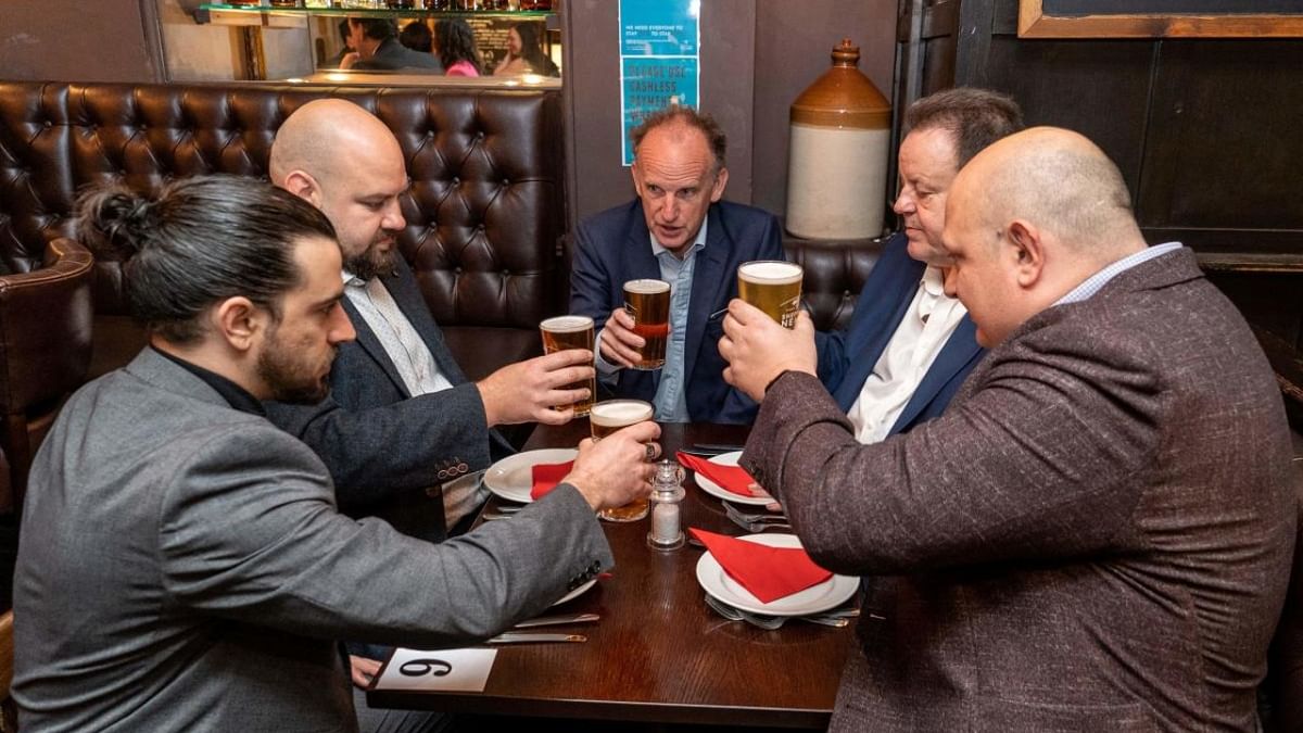 Customers sit with their drinks inside the re-opened 'Old Dr Butler’s Head' pub in London as Covid-19 lockdown restrictions ease across the country. Credit: AFP Photo
