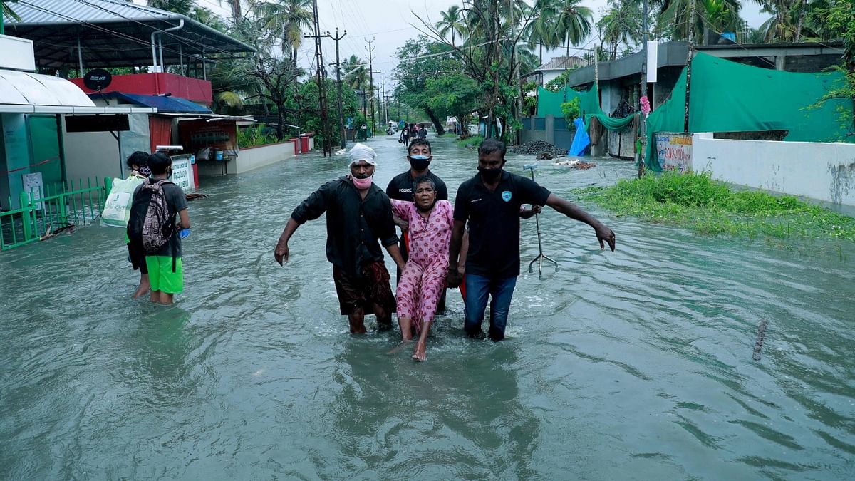 Police and rescue personnel evacuate a local resident through a flooded street in a coastal area after heavy rains under the influence of cyclone Tauktae in Kochi. Credit: AFP