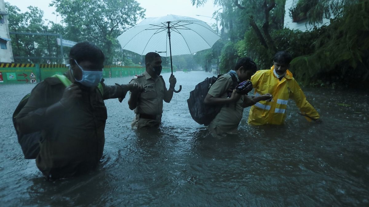 Frontline workers help people cross a flooded street after heavy rainfall caused by Cyclone Tauktae in Mumbai. Credit: Reuters