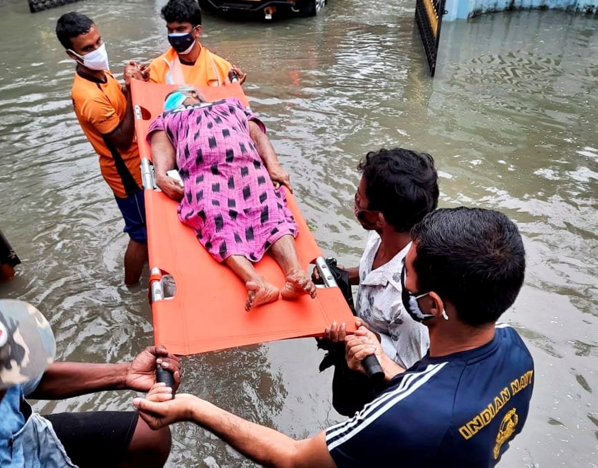 Naval officers from INS Dronacharya with people of the area rescue an old woman, after heavy rain at Chellanam panchayat in Ernakulam district, Kochi. Credit: PTI