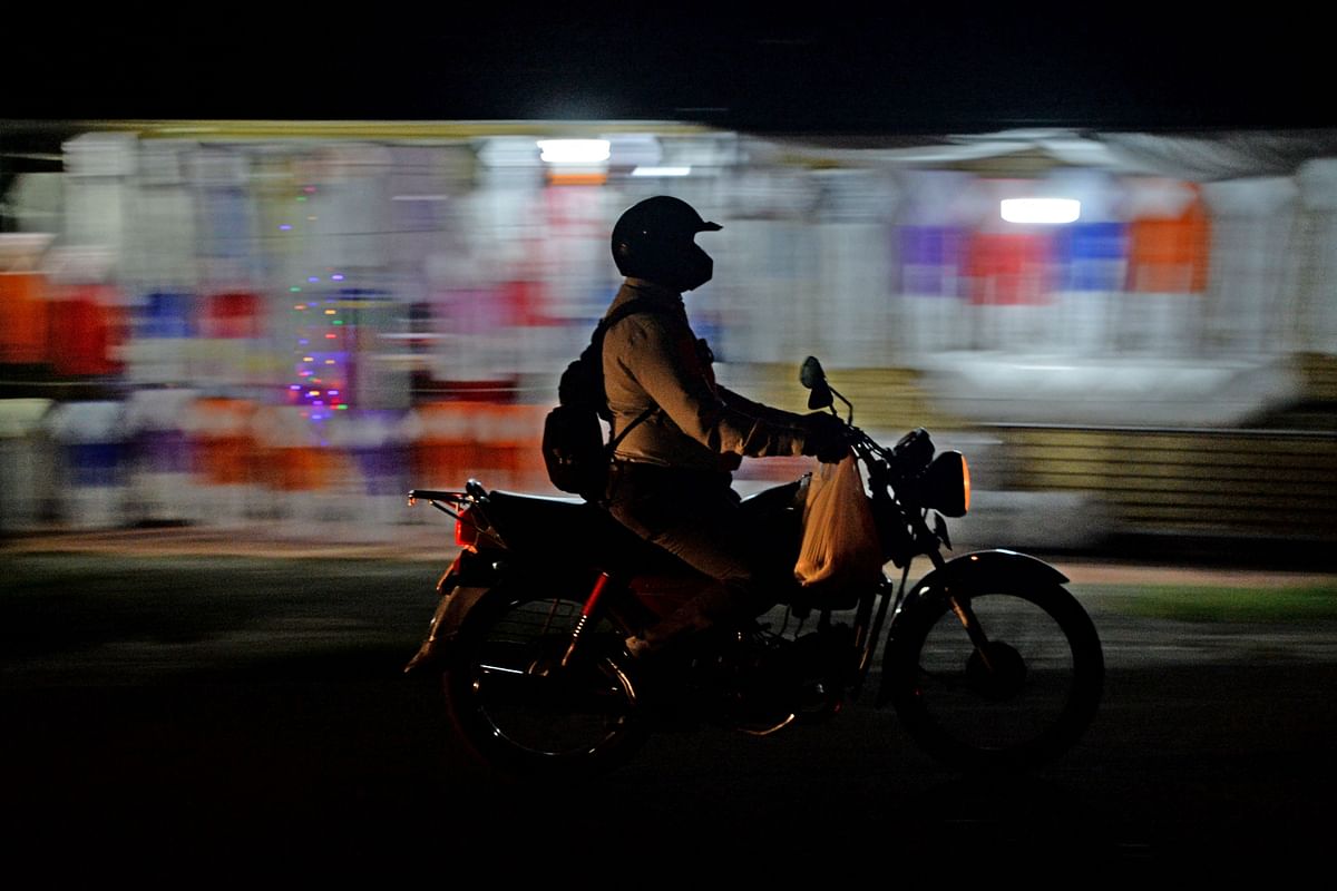 A motorist is seen as he drives past on the backdrop of street shops selling lanterns ahead of the Vesak festival, also known as Buddha Jayanti to commemorate the birth, enlightenment, and death of Gautama Buddha, in Colombo. Credit: AFP Photo