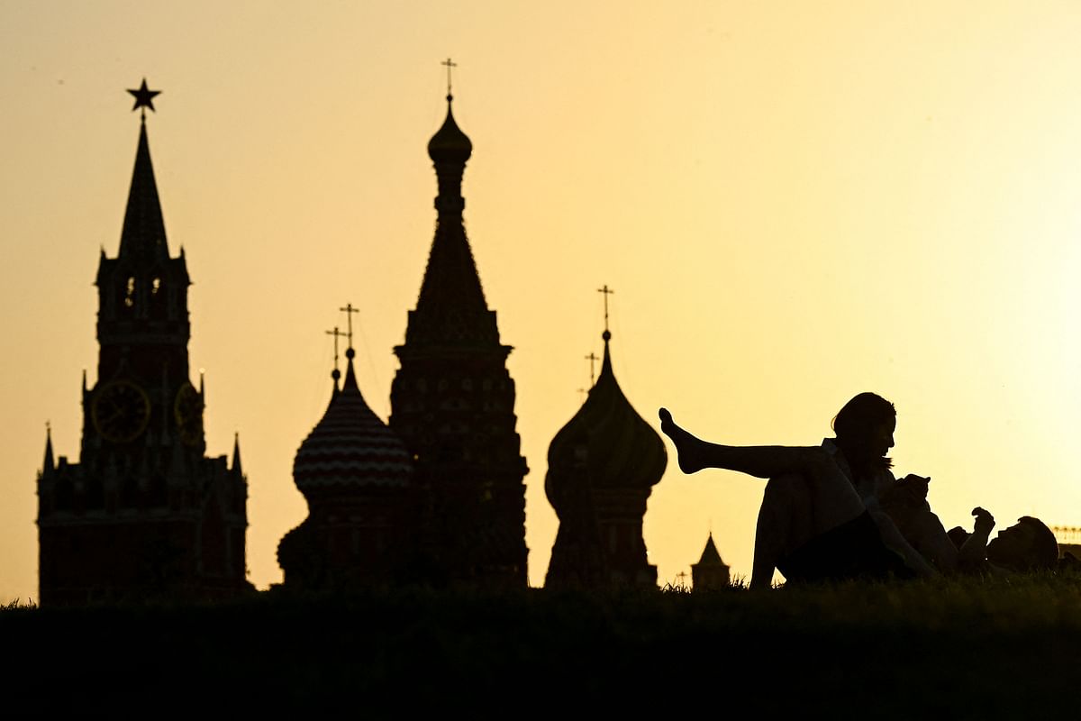 A couple rest in Zaryadye park in front of the Kremlin's Spasskaya tower and St Basil's cathedral during the sunset in downtown Moscow. Credit: AFP Photo