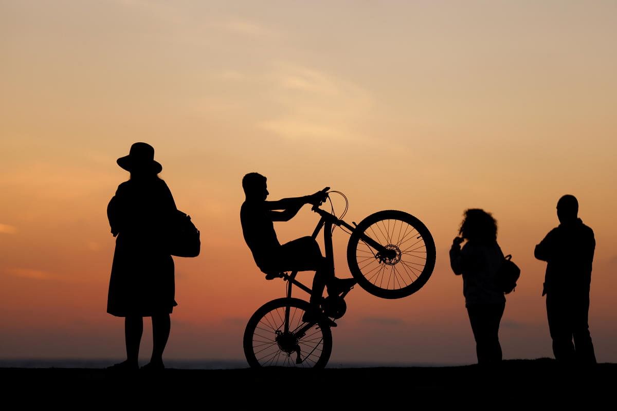 People are silhouetted as they visit on a promenade during sunset at a beach as the Israel-Hamas ceasefire holds, in Ashkelon, Israel. Credit: Reuters Photo
