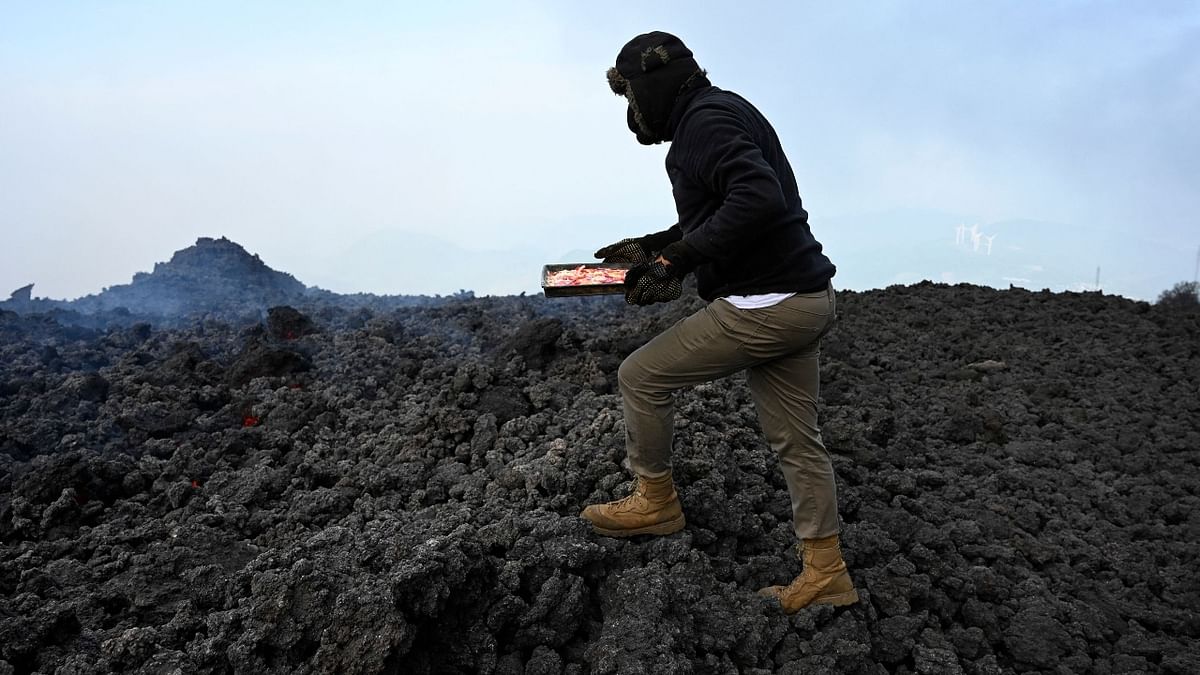 David Garcia places a pizza on a lava river that comes down from the Pacaya volcano.