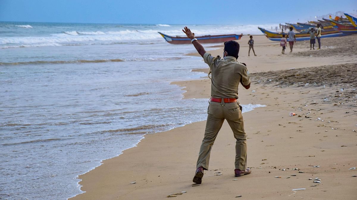A police person is seen making cyclone related warnings at Puri beach. Credit: PTI Photo