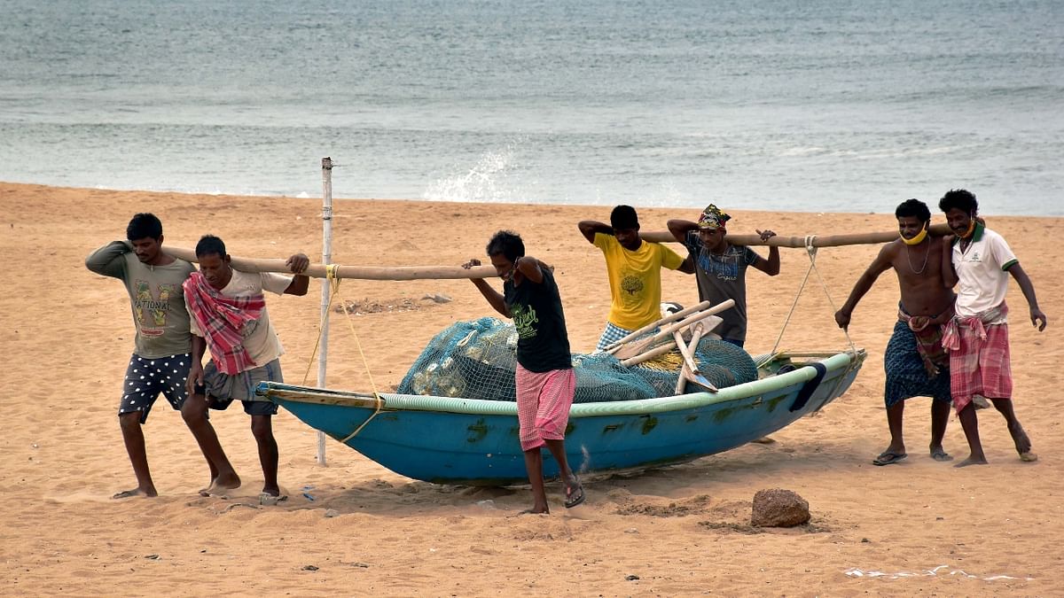 Fishermen carry a boat to a safe place ahead of cyclone Yaas at Puri beach. Credit: PTI