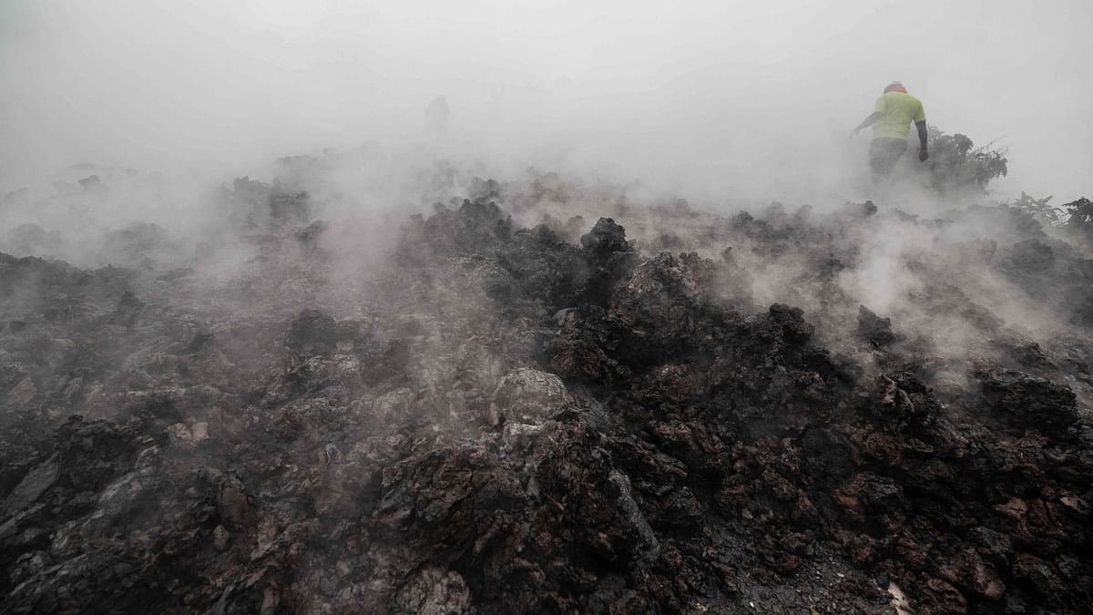 Residents walk through the smoke from smoldering lava flowing from Mount Nyiragongo in Goma.