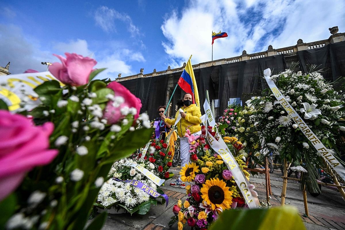 A woman holds a Colombian flag amid wreaths in honour of people killed during protests against the government placed outside the Congress building during a session in which Colombian Defense Minister Diego Molano's censure motion is discussed, in Bogota on May 24, 2021. Credit: AFP Photo