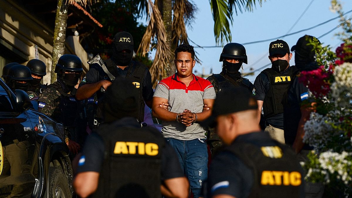 Members of the Criminal Investigation Technical Agency (ATIC) and agents of the Military Police of Public Order (PMOP) escort an alleged leader of the Mara Salvatrucha (MS-13) gang after his arrest in Tegucigalpa. Credit: AFP Photo