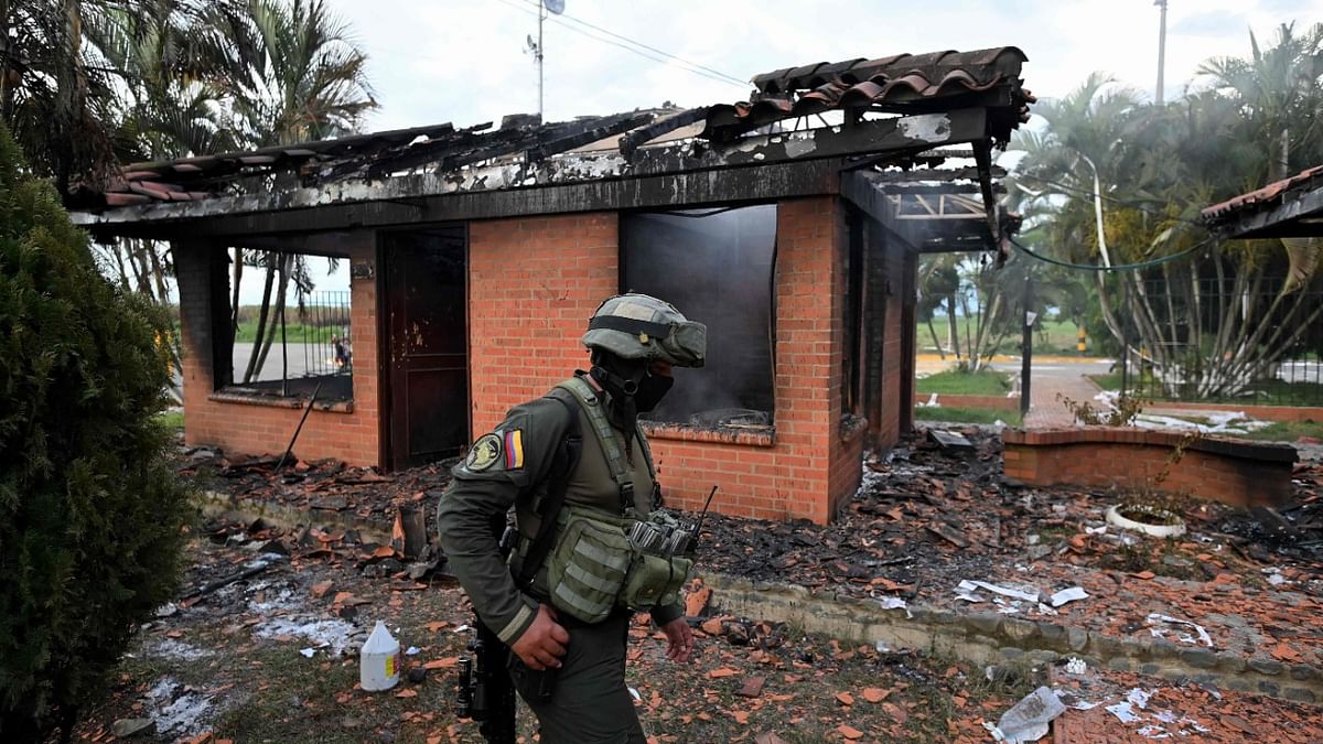 A policeman walks near the offices by a toll booth which was burnt in the framework of protests against the government of President Ivan Duque, on the Panamerican highway, in Villa Rica, Colombia. Credit: AFP Photo