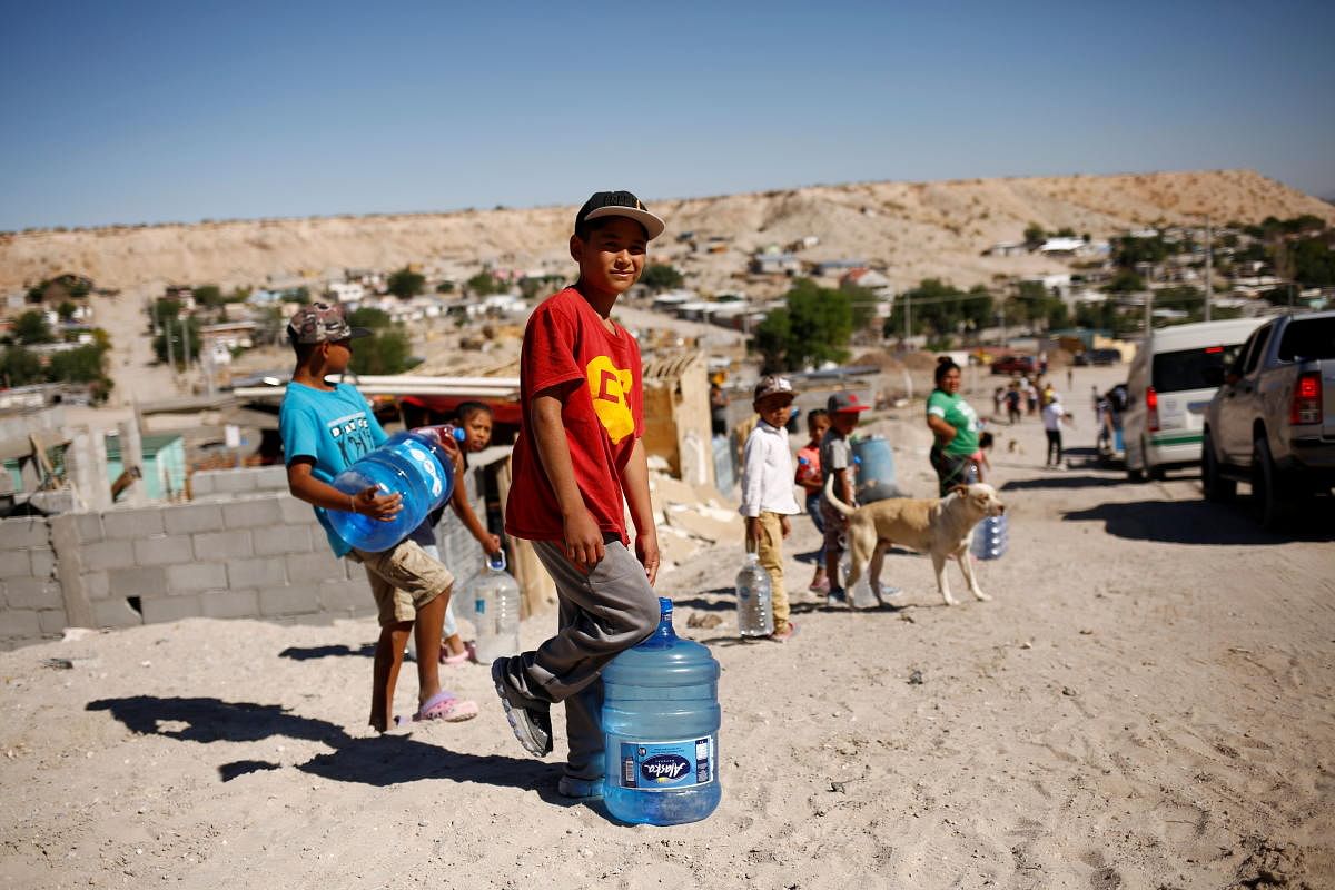 Children carry bottles of drinking water given by high school students in support of neighborhoods with lack of potable water, in Ciudad Juarez, Mexico. Credit: Reuters Photo