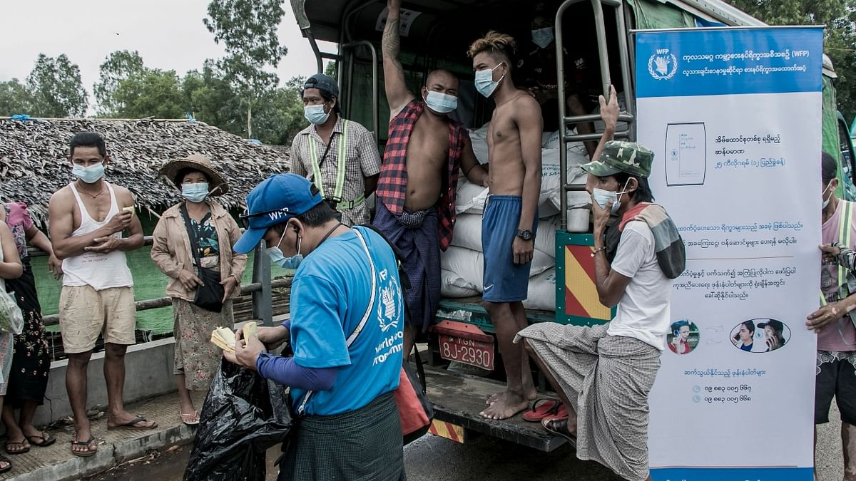 People wait to receive bags of rice distributed by the World Food Programme (WFP) as part of food aid efforts in Yangon.