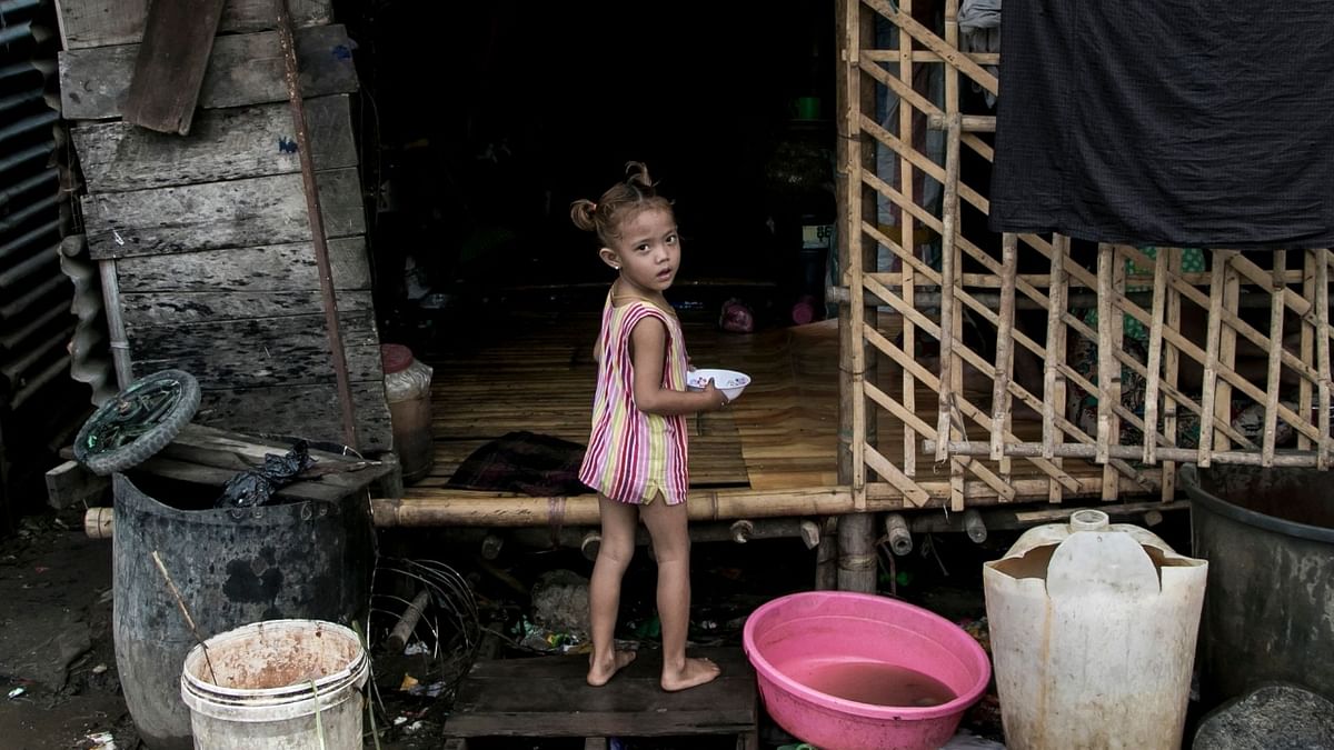 A girl plays in front of her home in a poor community on the outskirts of Yangon.