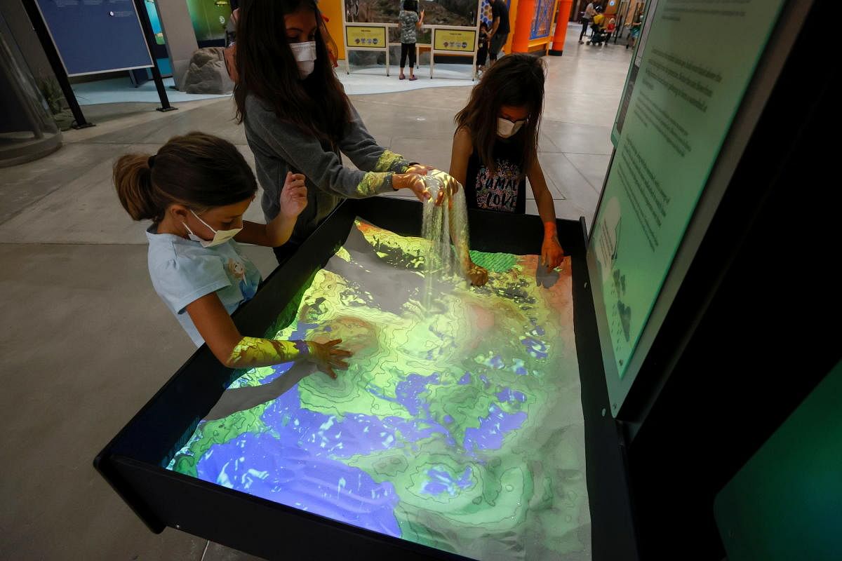 Visitors interact with the installation Earth's Features at the Discovery Cube Los Angeles museum on its reopening day in Sylmar, California, US. Credit: Reuters Photo