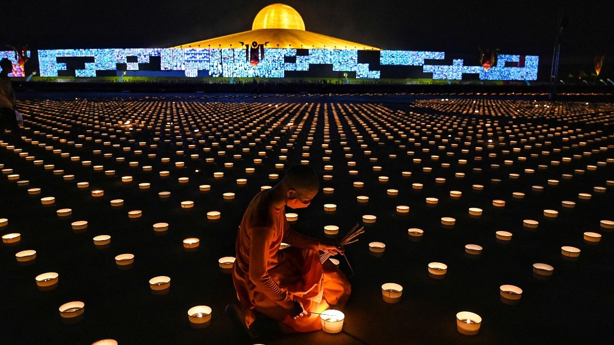 A Buddhist monk lights candles to commemorate Visakha Bucha Day or Vesak Day, a celebration of the birth, enlightenment and death of the Lord Buddha held on the full moon of the third lunar month in the Buddhist calendar, at Wat Dhammakaya Buddhist temple on the outskirts of Bangkok.