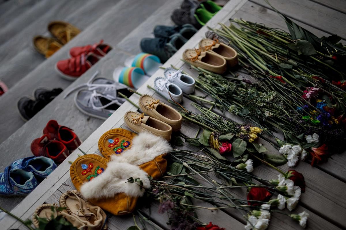 Flowers, shoes, and moccasins sit on the steps of the main entrance of The Mohawk Institute, a former residential school for First Nation kids, to honour the 215 children who's remains were recently discovered in a mass grave, in Brantford, Ontario, Canada. Credit: AFP Photo