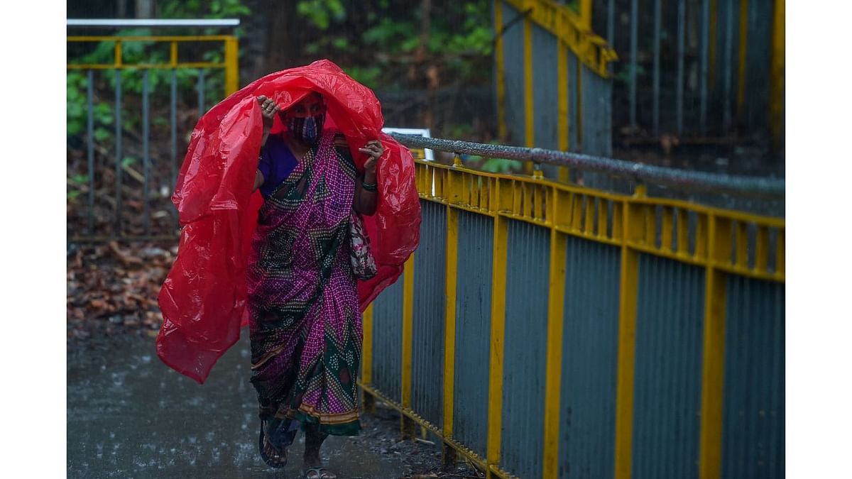 A woman covers herself with a plastic sheet during heavy monsoon rains in Mumbai. Credit: AFP Photo