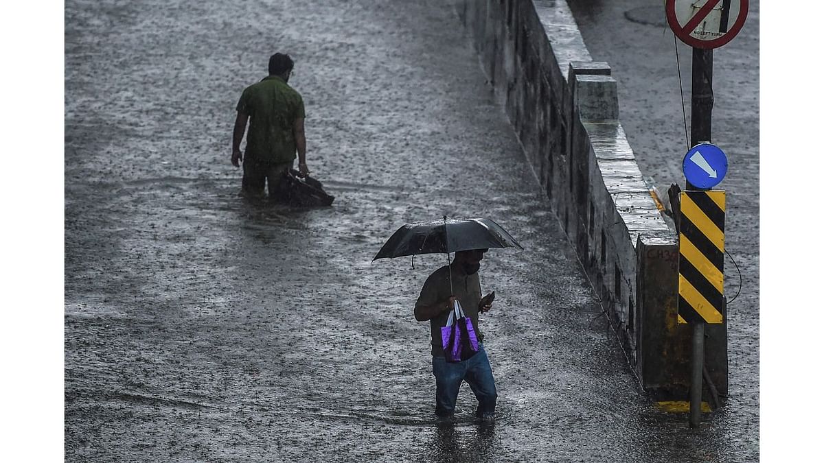 People walk on a flooded road during heavy monsoon rains in Mumbai. Credit: AFP Photo