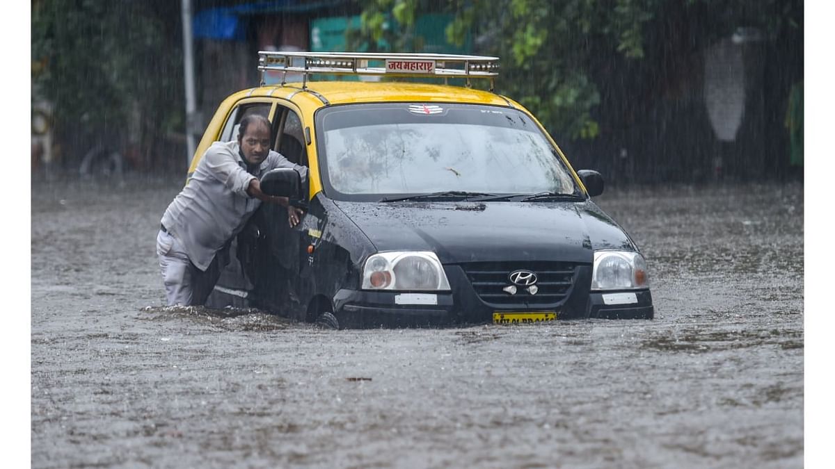While there were fewer vehicles on the city roads amid the downpour, motorcyclists and other two-wheeler riders were unable to manoeuvre their vehicles at some of the flooded places. In this photo, a taxi driver is seen pushing his car which got stuck in water due to heavy downpour. Credit: PTI Photo
