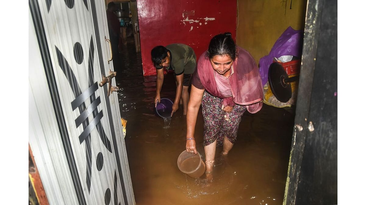 A woman takes water out of the house after heavy rain, in Thane. Credit PTI Photo