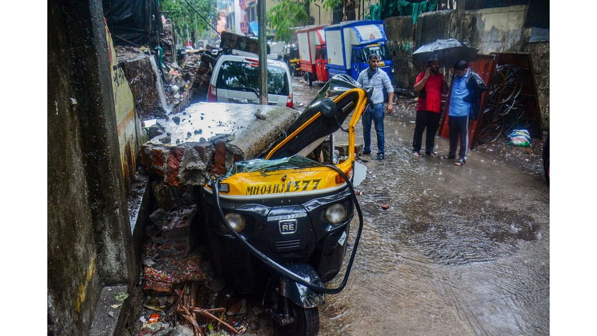 Vehicles damaged after a society compound wall fell on them following heavy rain. Credit: PTI Photo