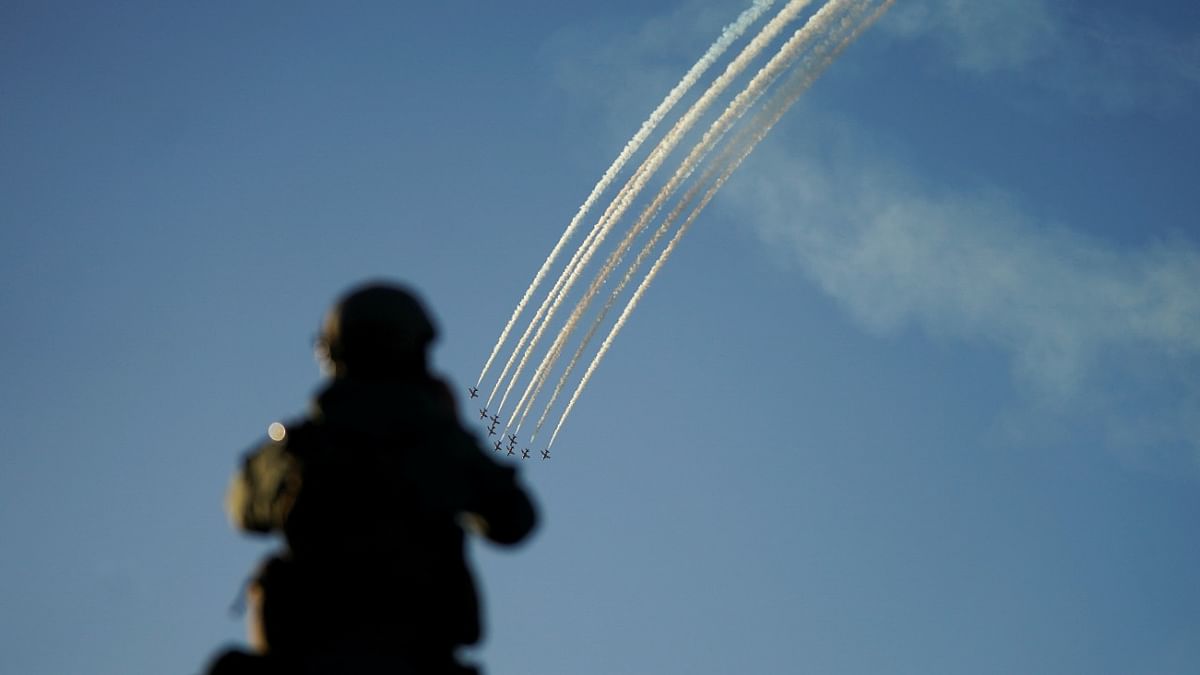 A member of a security detail watches the Royal Air Force aerobatic team, the Red Arrows, perform over Carbis Bay during the G7 summit in Cornwall, Britain. Credit: Reuters Photo