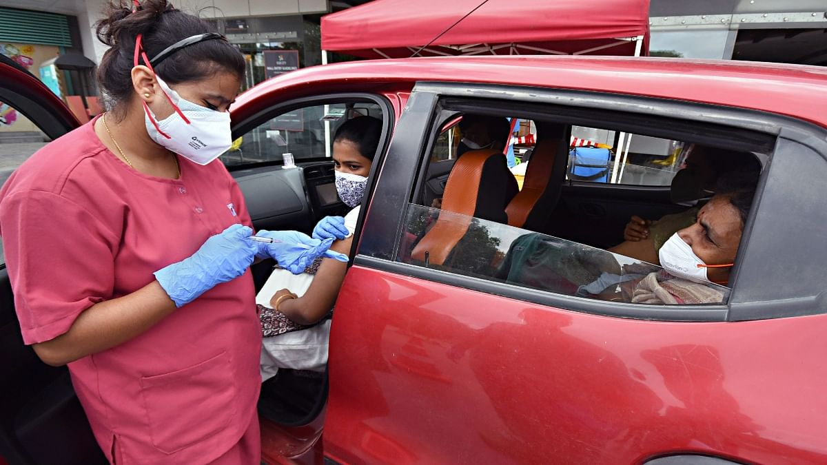 A health worker administers a dose of Covid-19 vaccine at a drive-through vaccination site set up at Vega City mall, Bannerghatta road. Credit: DH Photo