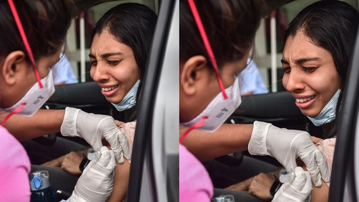 A health worker administers a dose of Covid-19 vaccine to a woman as she reacts during the drive-in vaccination drive in Bengaluru. Credit: PTI Photo