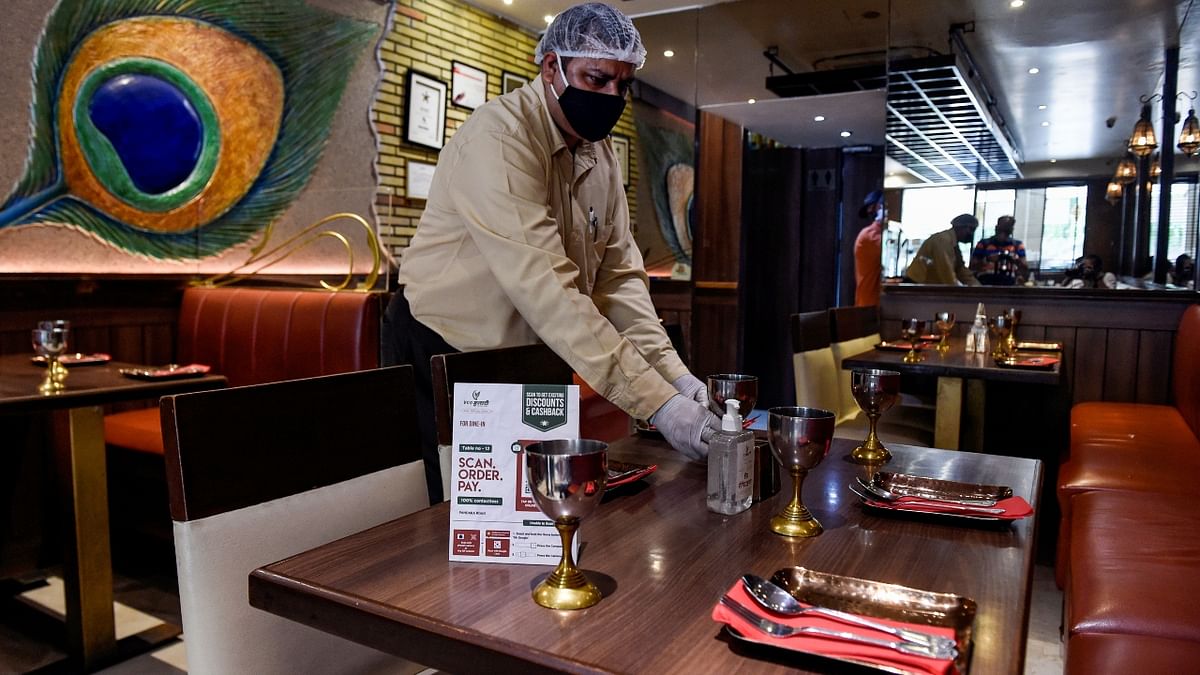 A waiter sets a table in a restaurant that opened after the state government eased Covid-induced restrictions, in New Delhi.