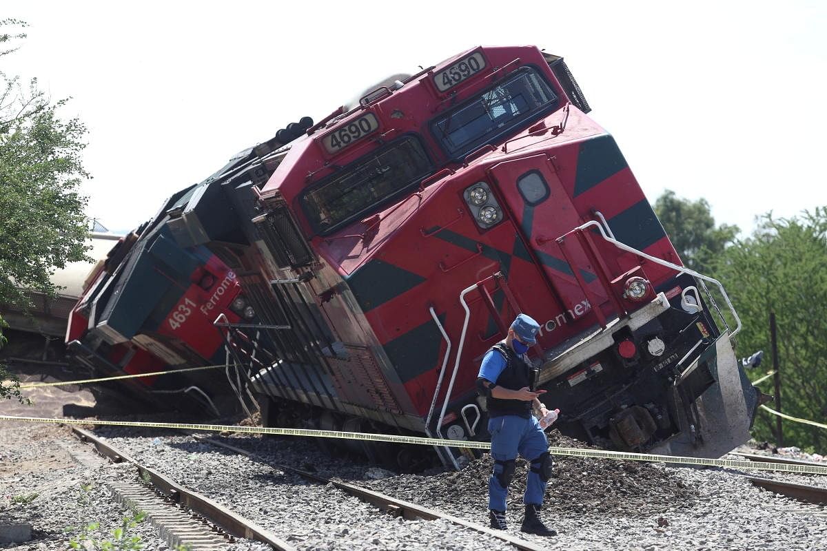 A police officer checks his phone while walking at the scene where a freight train derailed onto houses in the rural area of San Isidro Mazatepec, in Jalisco state, Mexico. Credit: Reuters Photo