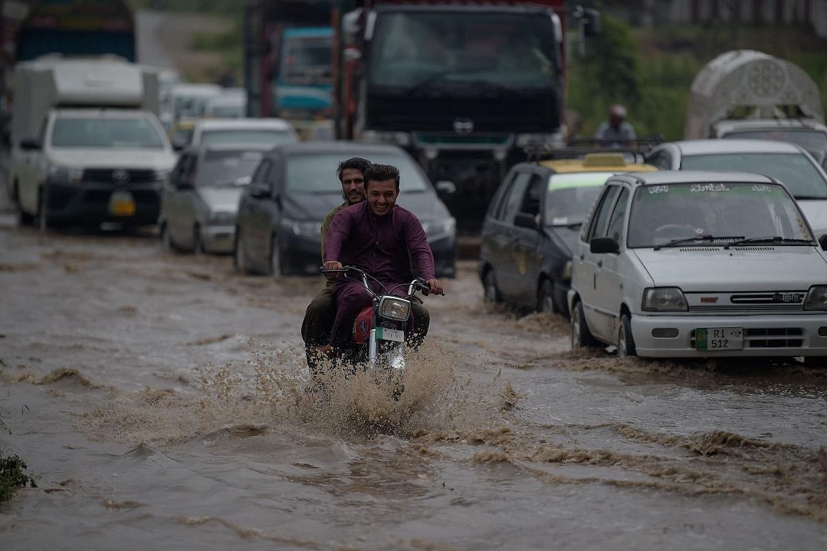 Commuters ride along a waterlogged street following a heavy rainfall on the outskirts of Islamabad. Credit: AFP Photo
